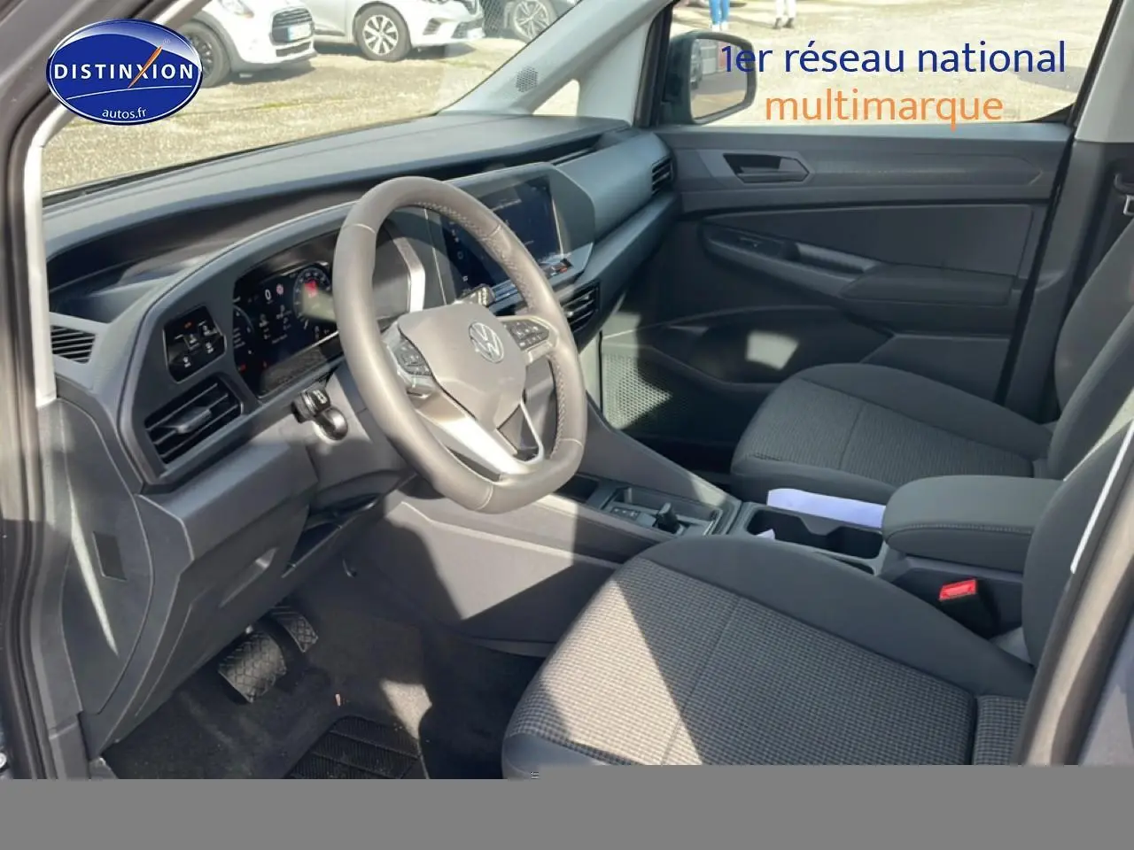 Intérieur avant droit du Volkswagen Caddy 2025 gris pur, volant cuir multifonction et sièges tissu noir titane.
