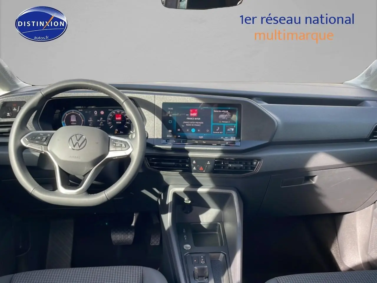 Vue intérieure du tableau de bord du Volkswagen Caddy gris pur 2025, avec volant cuir multifonction et écran tactile central.