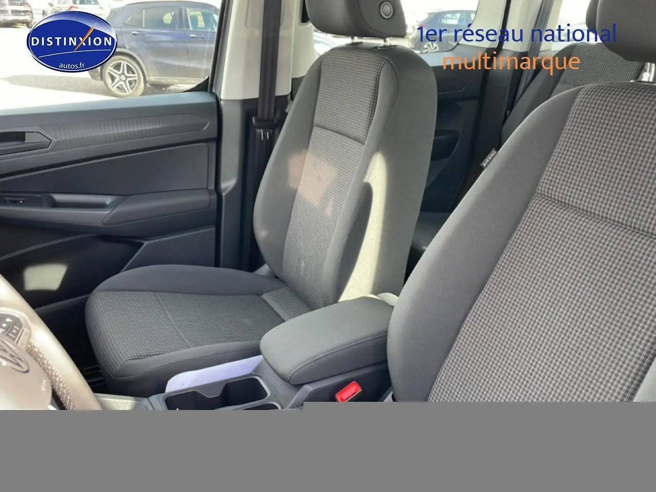 Vue intérieure côté conducteur du Volkswagen Caddy 2025 gris pur, sièges tissu noir titane avec accoudoirs réglables.