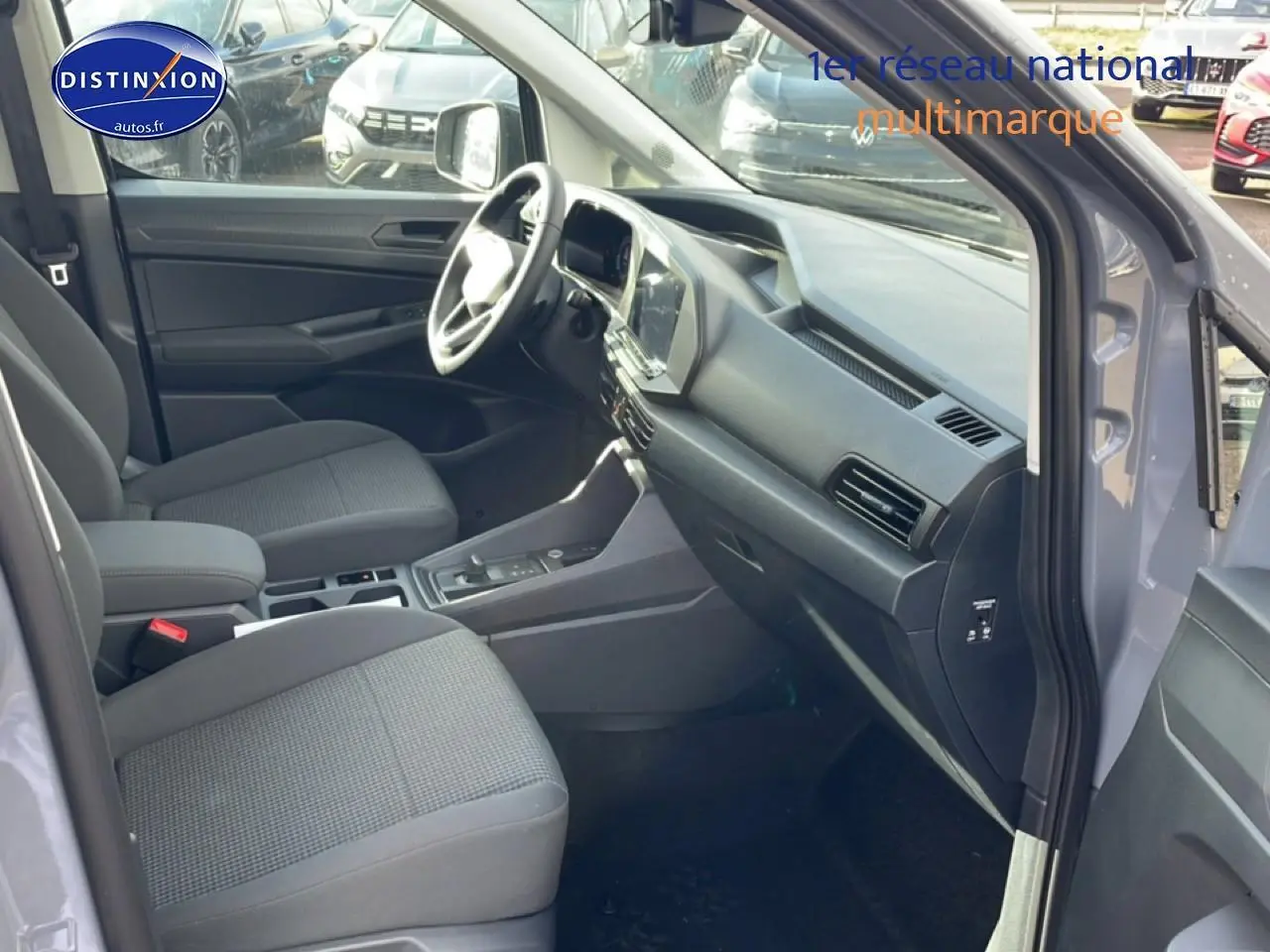 Intérieur avant droit du Volkswagen Caddy gris pur 2025, sièges tissu noir titane et tableau de bord moderne.