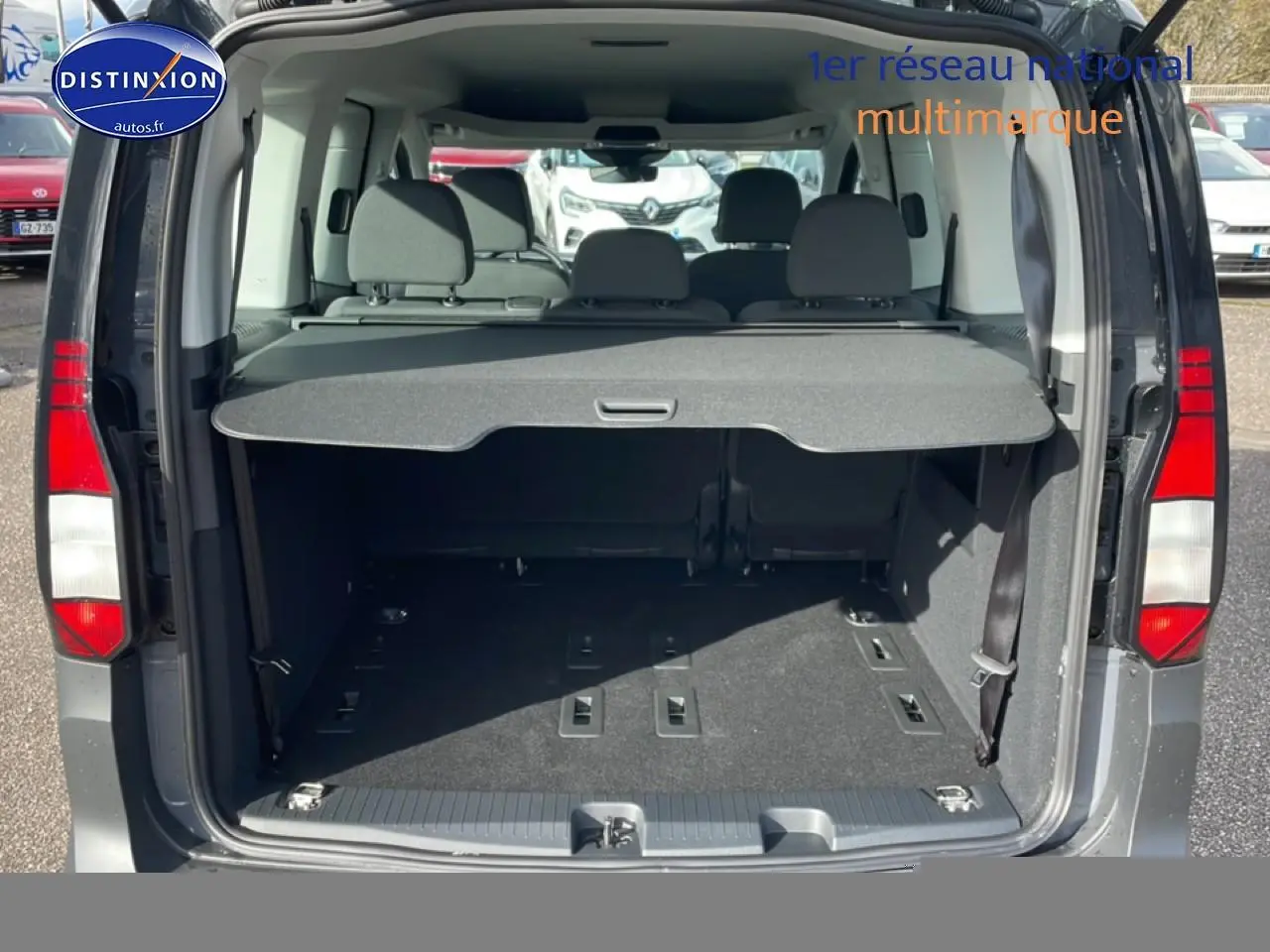 Vue arrière ouverte du Volkswagen Caddy gris pur 2025, montrant le coffre spacieux avec cache-bagages et banquette arrière.