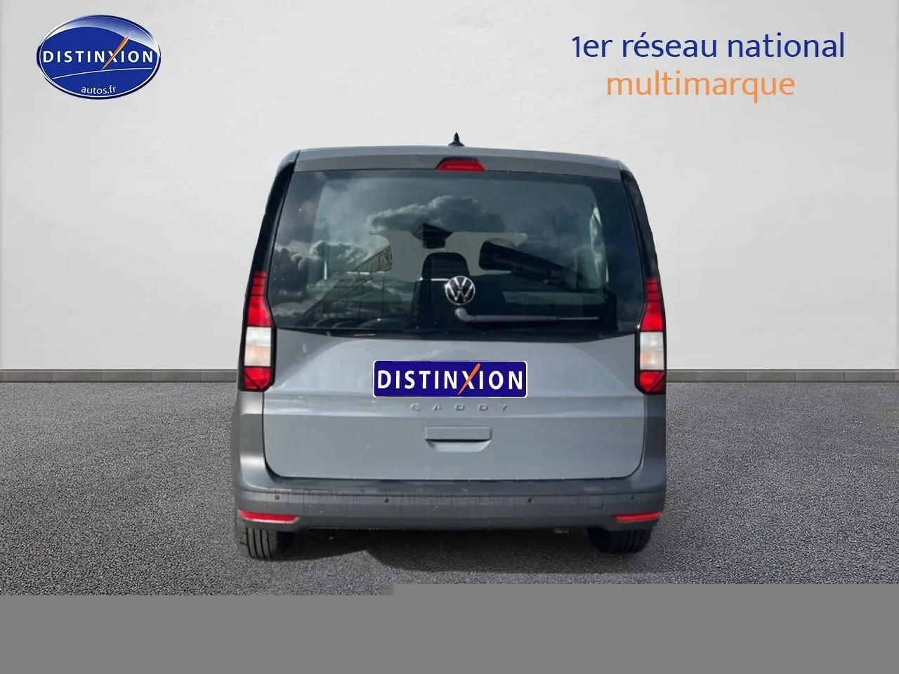 Vue arrière d'un Volkswagen Caddy gris pur 2025 avec vitres teintées et feux verticaux rouges.