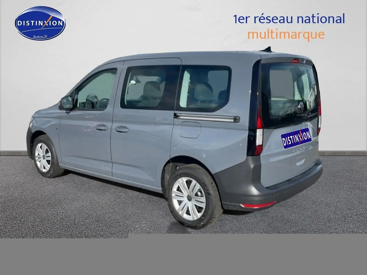 Vue 3/4 arrière droite d'un Volkswagen Caddy gris pur avec vitres teintées et barres de toit noires.