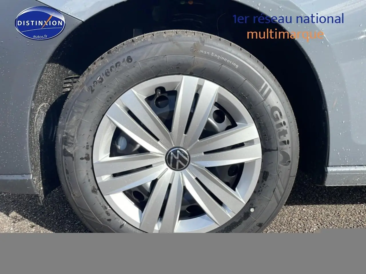 Gros plan sur la roue avant droite d’un Volkswagen Caddy gris pur avec jante argentée et logo VW central.