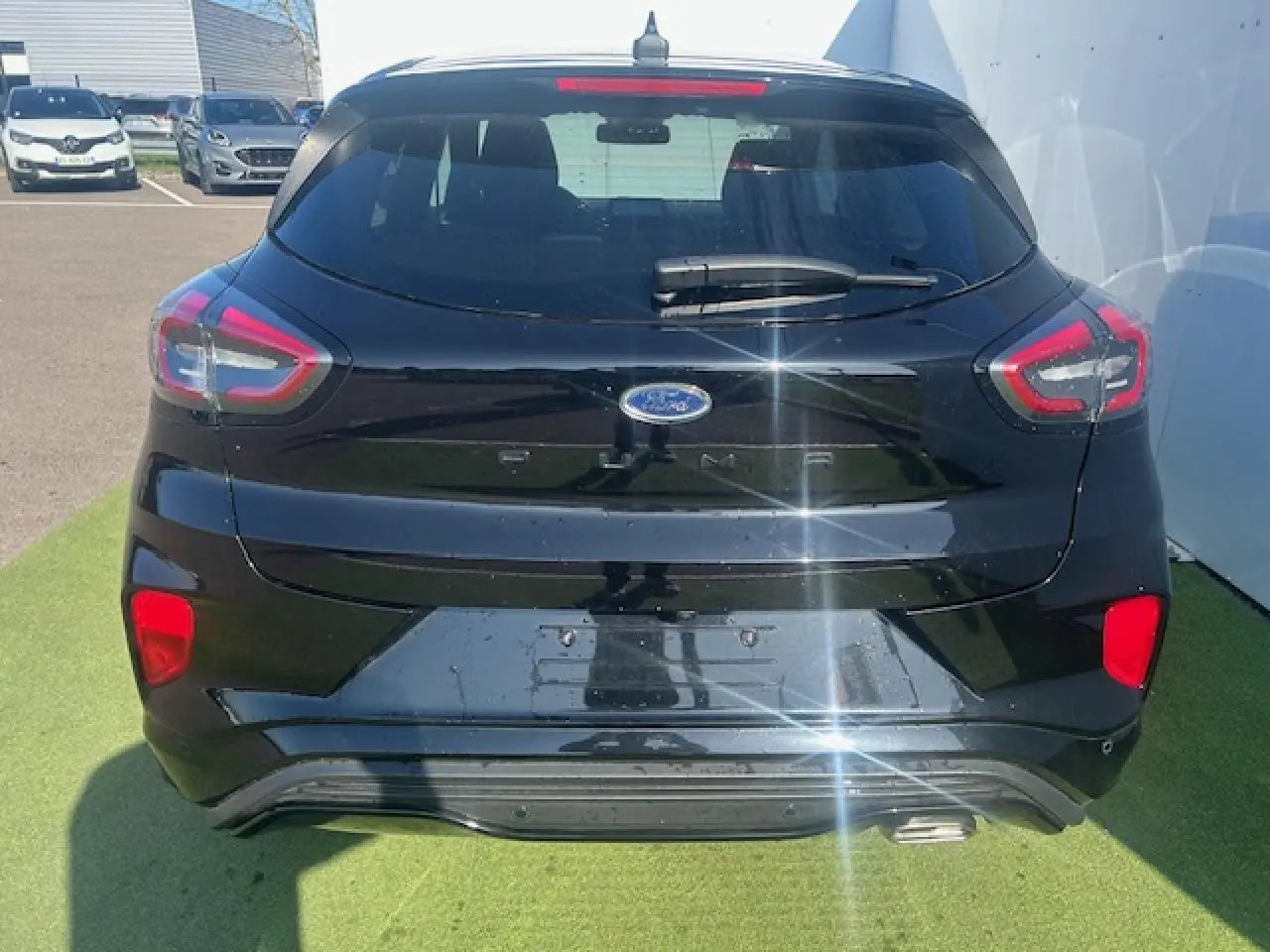 Vue arrière d'un Ford Puma noir Agate 2023 avec feux LED et hayon électrique mains libres visible au soleil.