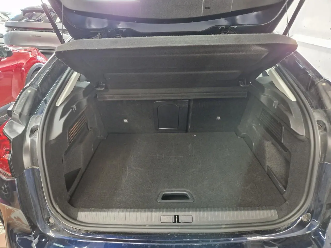 Coffre ouvert en vue arrière d'une Citroën C4 2024 bleu Eclipse avec intérieur noir et trappe à skis visible.