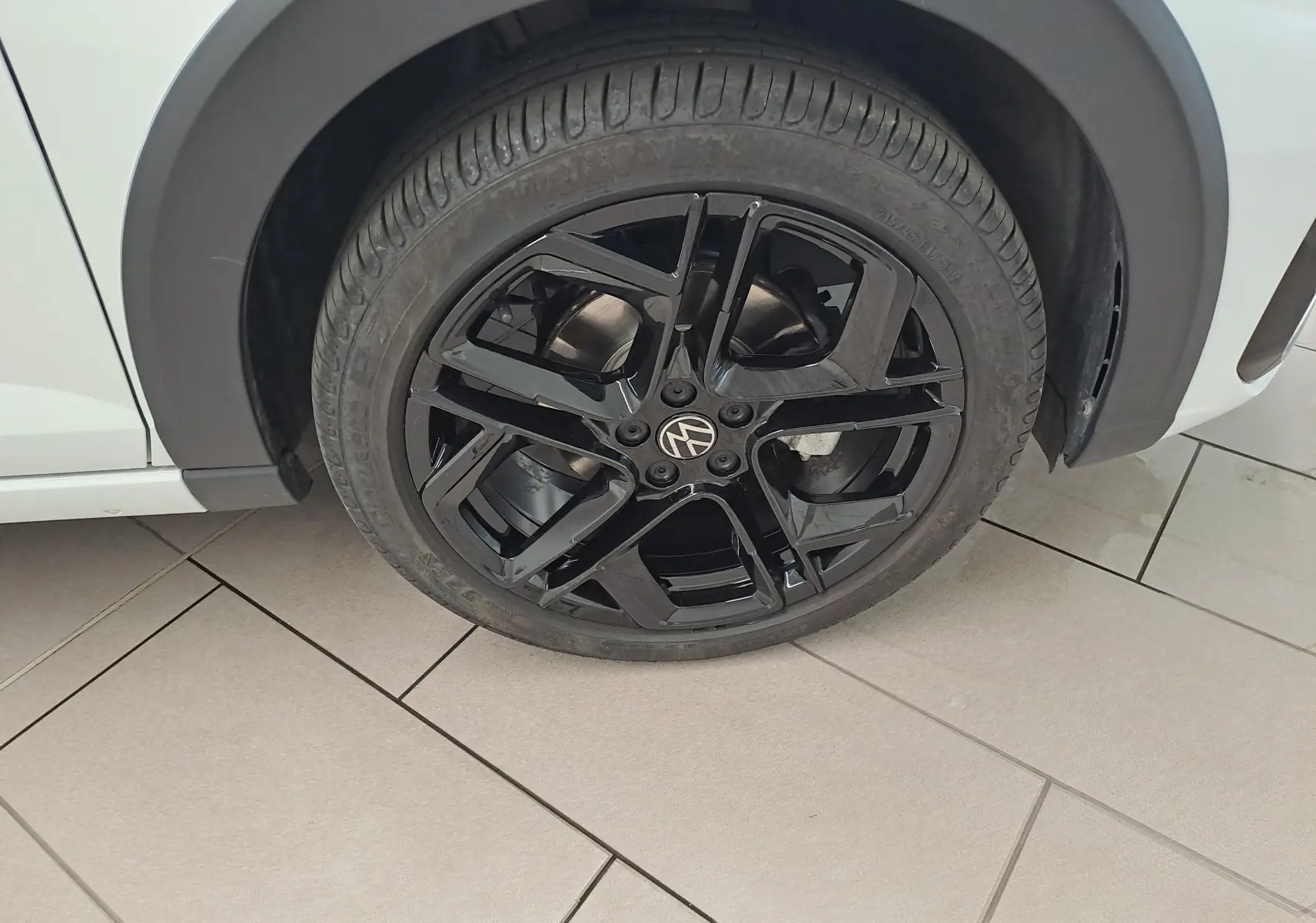 Gros plan sur la jante noire en alliage 18 pouces York du côté gauche d’un Volkswagen Taigo blanc toit noir.