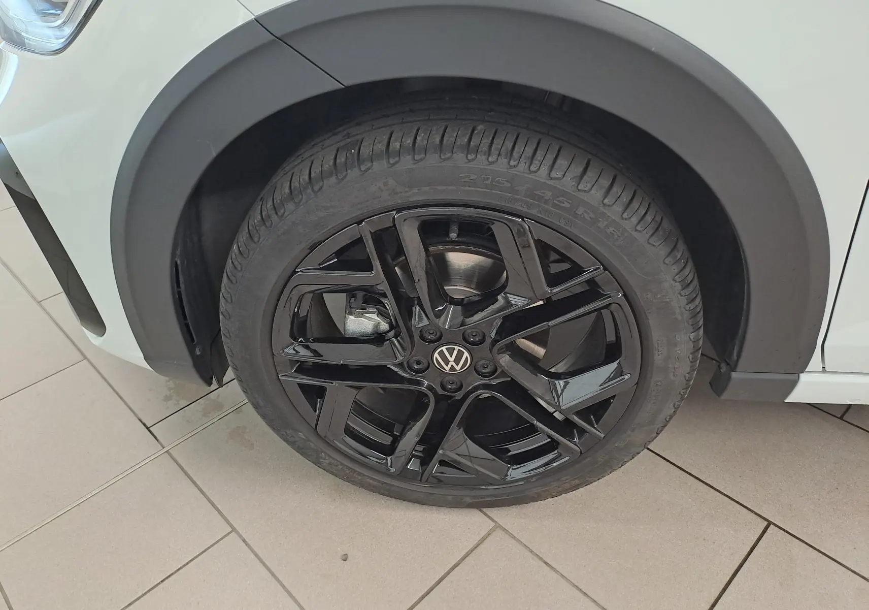 Gros plan sur la jante noire en alliage 18 pouces du Volkswagen Taigo blanc pur, avec logo VW au centre.