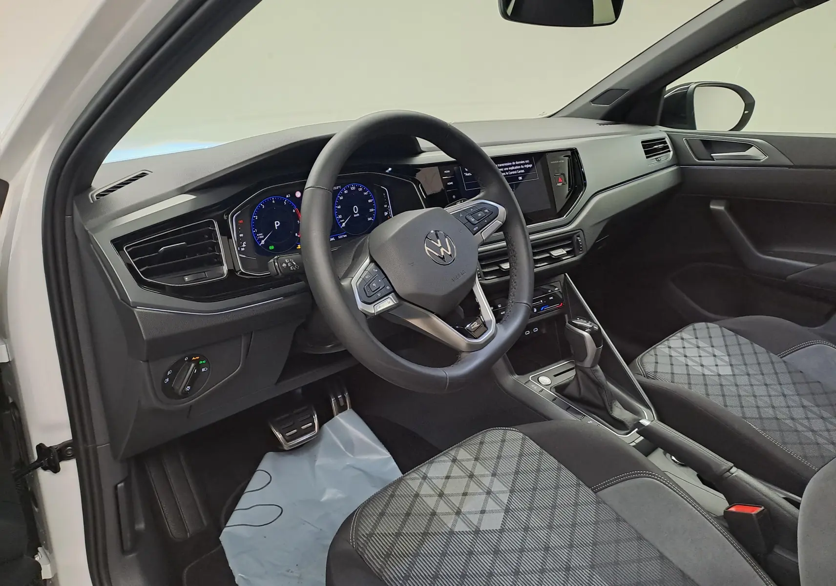 Vue intérieure côté conducteur du Volkswagen Taigo 2025, volant cuir multifonctions et sièges tissu à motif gris.