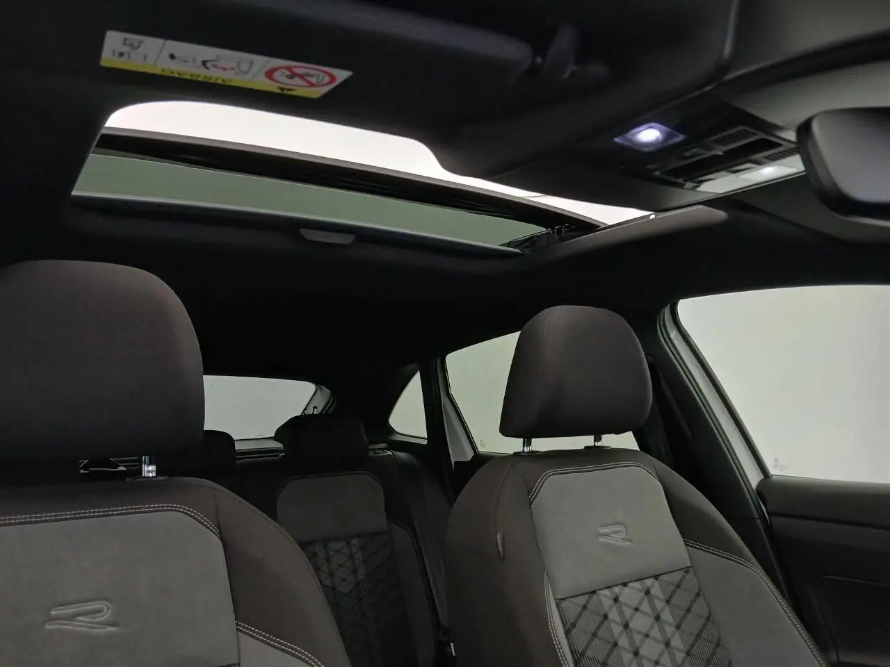Vue intérieure du Volkswagen Taigo R-Line 2025, sièges noirs avec logo R et toit ouvrant en verre ouvert.