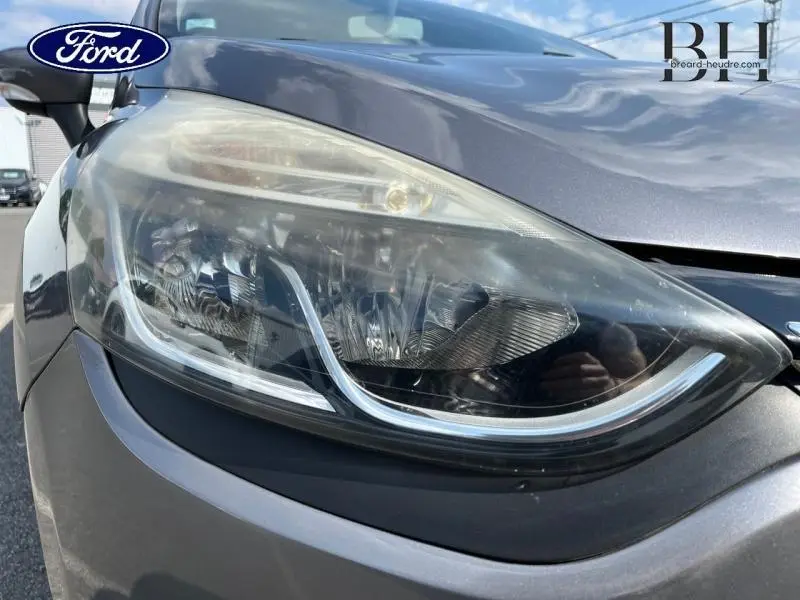 Gros plan sur le phare avant gauche d’une Renault Clio gris Cassiopée, mettant en valeur les détails du bloc optique.