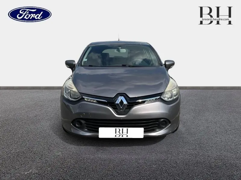 Vue avant d'une Renault Clio gris Cassiopée de 2013, avec logo Renault proéminent et phares halogènes allumés.