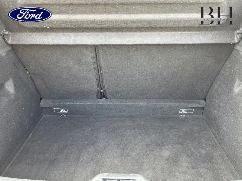 Coffre vide vu de face, revêtement tissu gris foncé, banquette arrière rabattable visible en arrière-plan.