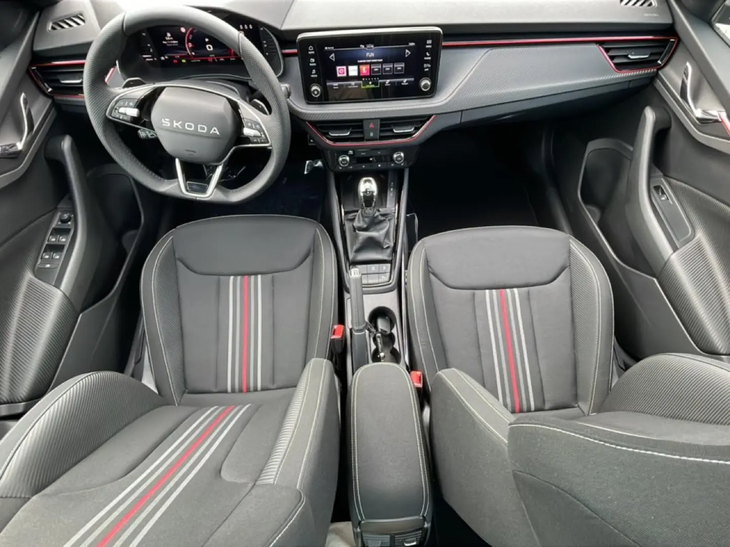 Vue intérieure frontale du Skoda Kamiq Monte Carlo 2026, sièges sport noirs avec bandes rouges et tableau de bord moderne.