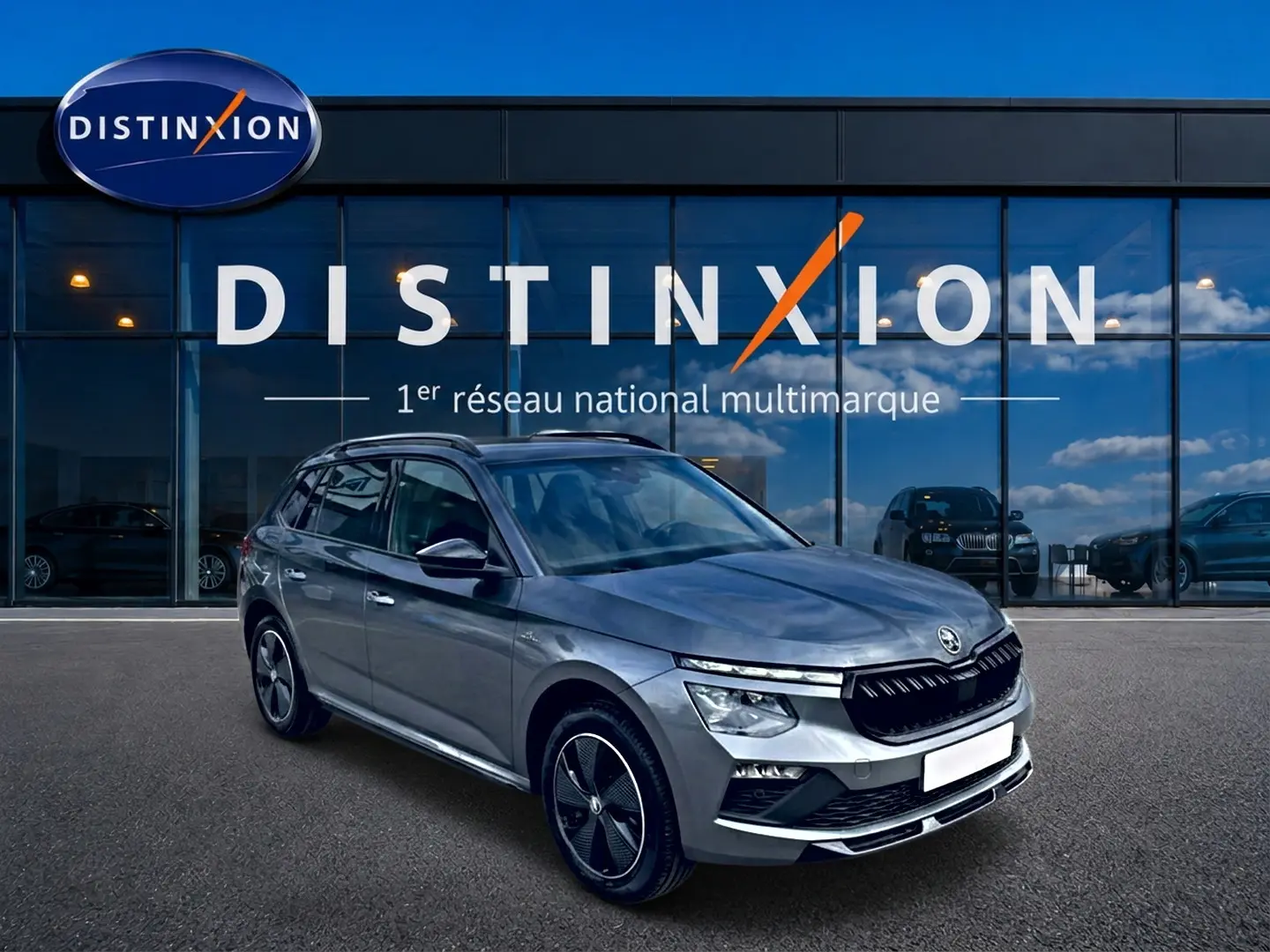 Vue 3/4 avant droite d'un Skoda Kamiq gris graphite avec jantes alu noires et toit panoramique en verre.