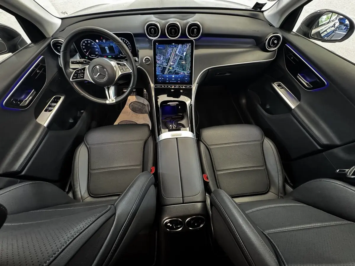 Intérieur Mercedes GLC 300 E 2023 vu de dessus, sièges cuir noirs et écran tactile central vertical lumineux.