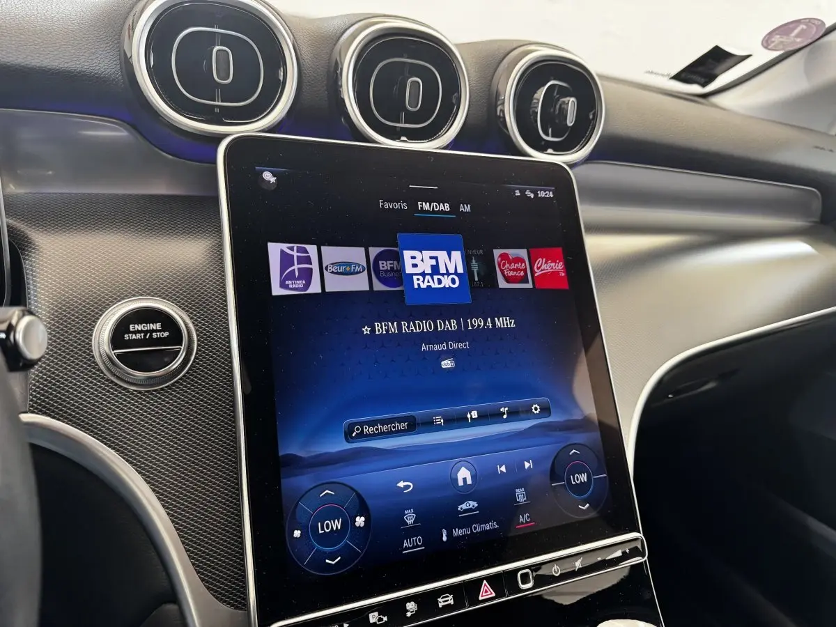 Vue rapprochée de l’écran tactile central et des aérateurs ronds du tableau de bord intérieur du Mercedes GLC gris foncé.