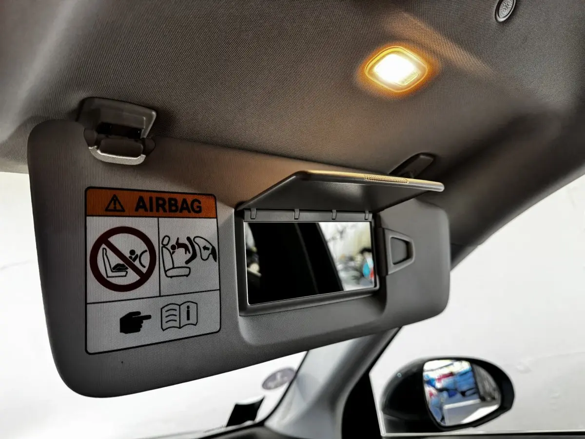 Détail du pare-soleil intérieur avec miroir et avertissement airbag dans un Mercedes GLC gris foncé, vue côté gauche.