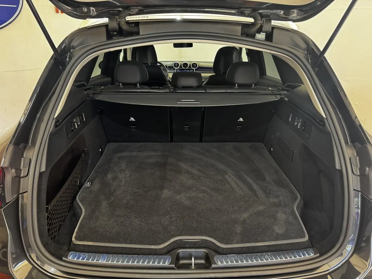 Coffre ouvert vu de l'arrière d'un Mercedes GLC 300 E Business Line gris foncé, avec tapis de coffre noir et intérieur spacieux.