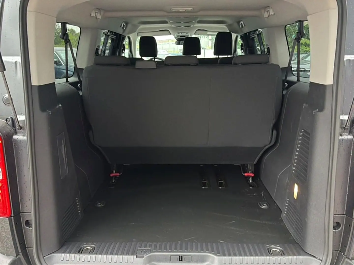 Vue arrière du coffre ouvert du Fiat Scudo Combi gris titane, montrant la banquette arrière et l'espace de chargement.