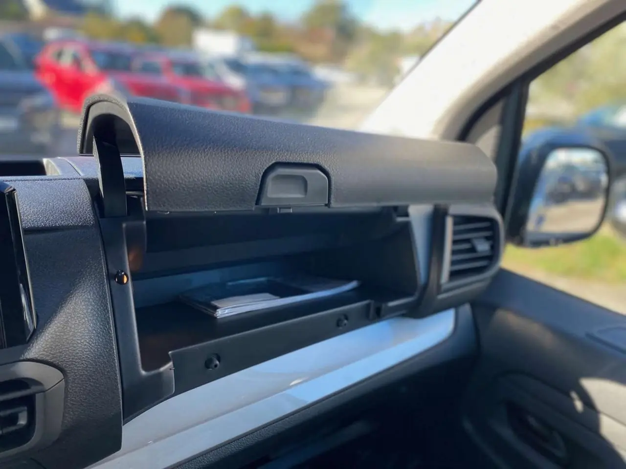 Intérieur du Peugeot Expert Fourgon 2026, vue sur la boîte à gants ouverte côté passager avec tableau de bord gris et noir.