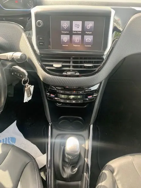 Vue intérieure centrée sur la console centrale du Peugeot 2008 gris, avec écran tactile et levier de vitesse manuel visible.