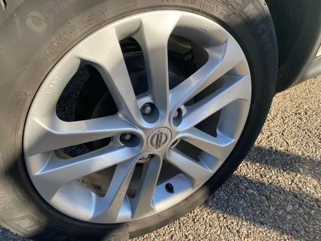 Gros plan sur la jante argentée et le pneu Michelin d'un Nissan Juke 1.5 110 CH N-Connecta 2018, posé sur sol goudronné.