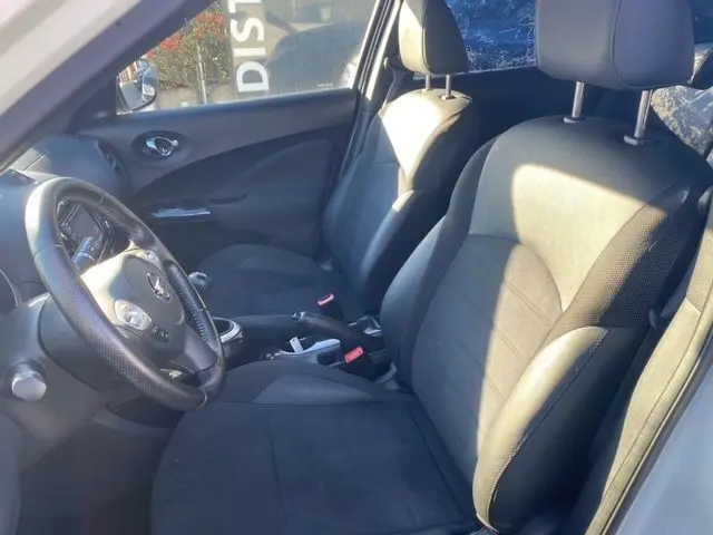 Intérieur avant du Nissan Juke 2018 N-Connecta, sièges noirs en tissu et volant multifonction côté gauche visible.