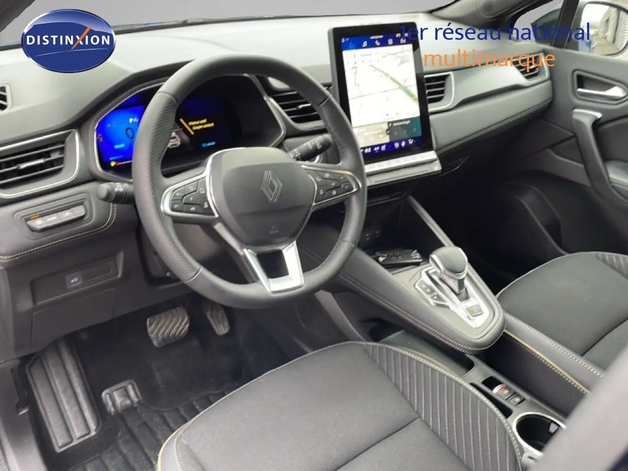 Vue intérieure côté conducteur de la Renault Symbioz 2025, tableau de bord noir avec écran tactile vertical et volant multifonction.