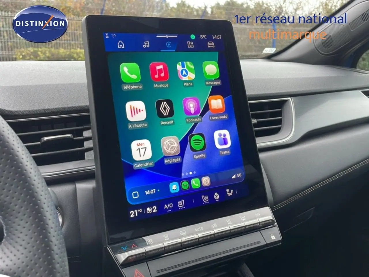 Vue intérieure centrée sur l'écran tactile vertical du tableau de bord d'une Renault Symbioz bleu iron metal, avec commandes climatisation visibles.