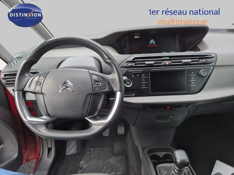 Vue intérieure du tableau de bord et volant cuir d'une Citroën Grand C4 Spacetourer rouge Rubi, avec écran tactile et boîte manuelle.