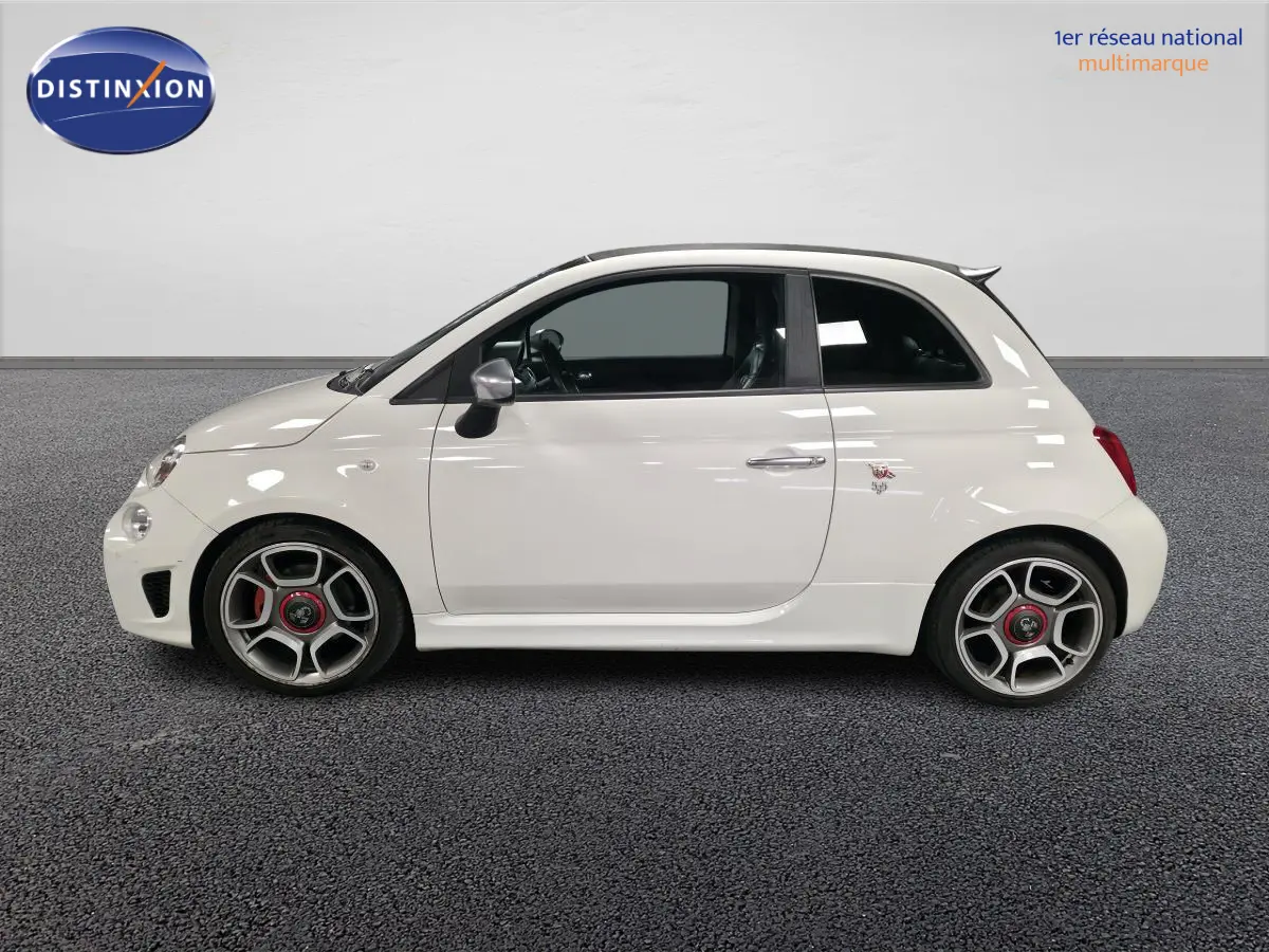Profil droit de l'Abarth 500 blanc avec étriers rouges et jantes alliage 17 pouces dans un showroom intérieur.