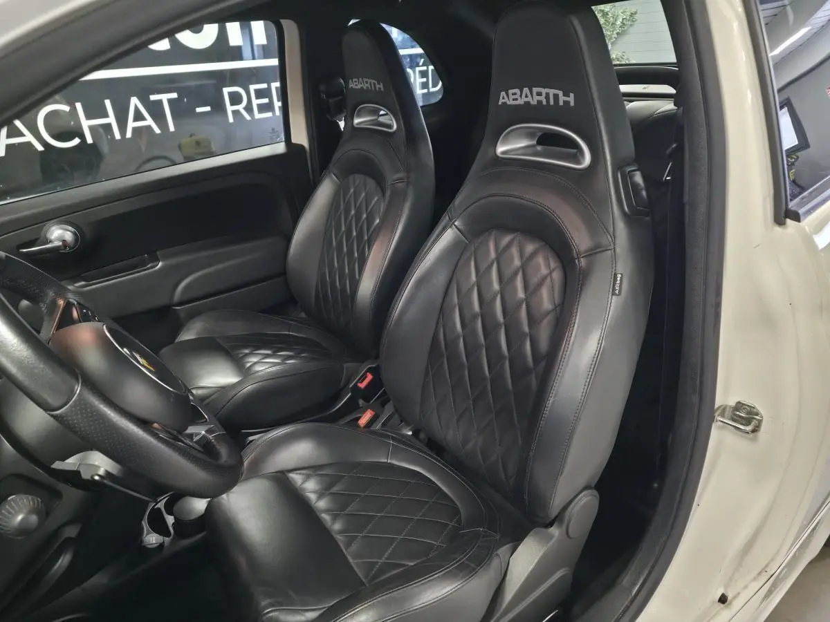Vue intérieure côté gauche montrant les sièges sport noirs en cuir avec logo ABARTH sur une Abarth 595C blanche.