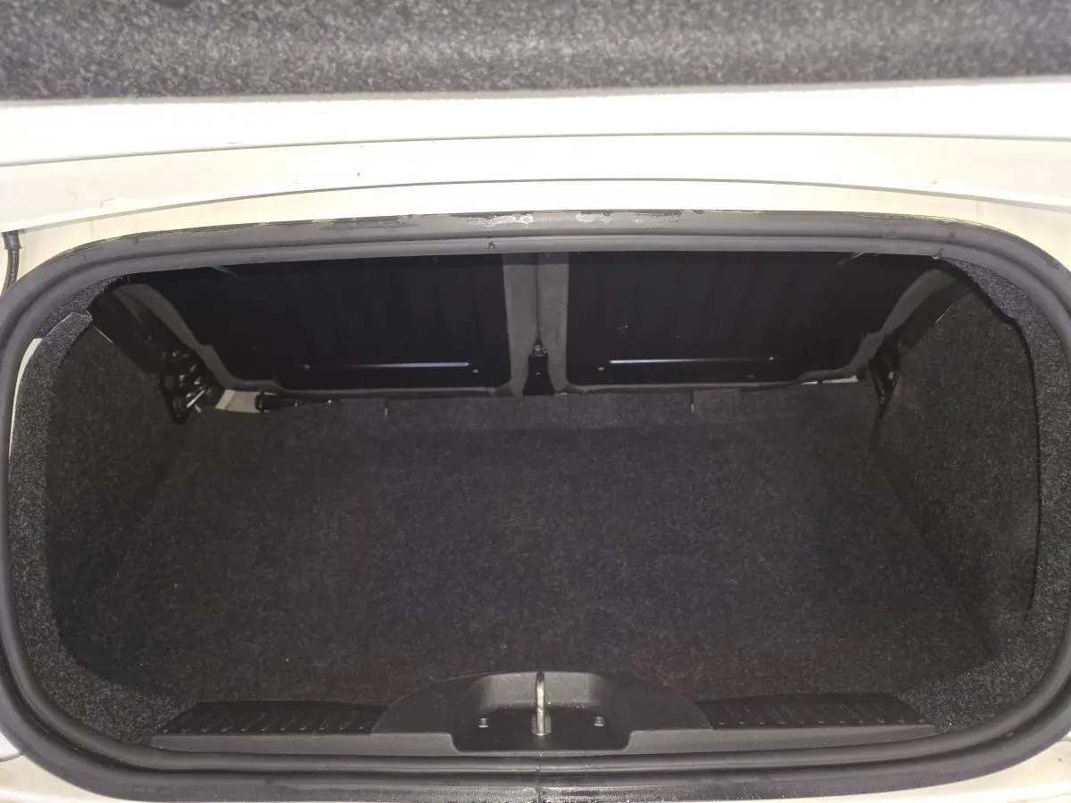 Coffre ouvert d'une Abarth 500 blanc Gara, montrant l'espace de rangement vide et la finition intérieure noire.