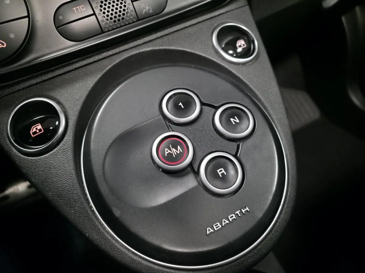 Gros plan sur la commande de lève-vitre et le bouton TTC sur la console centrale noire de l'Abarth 500 blanc.