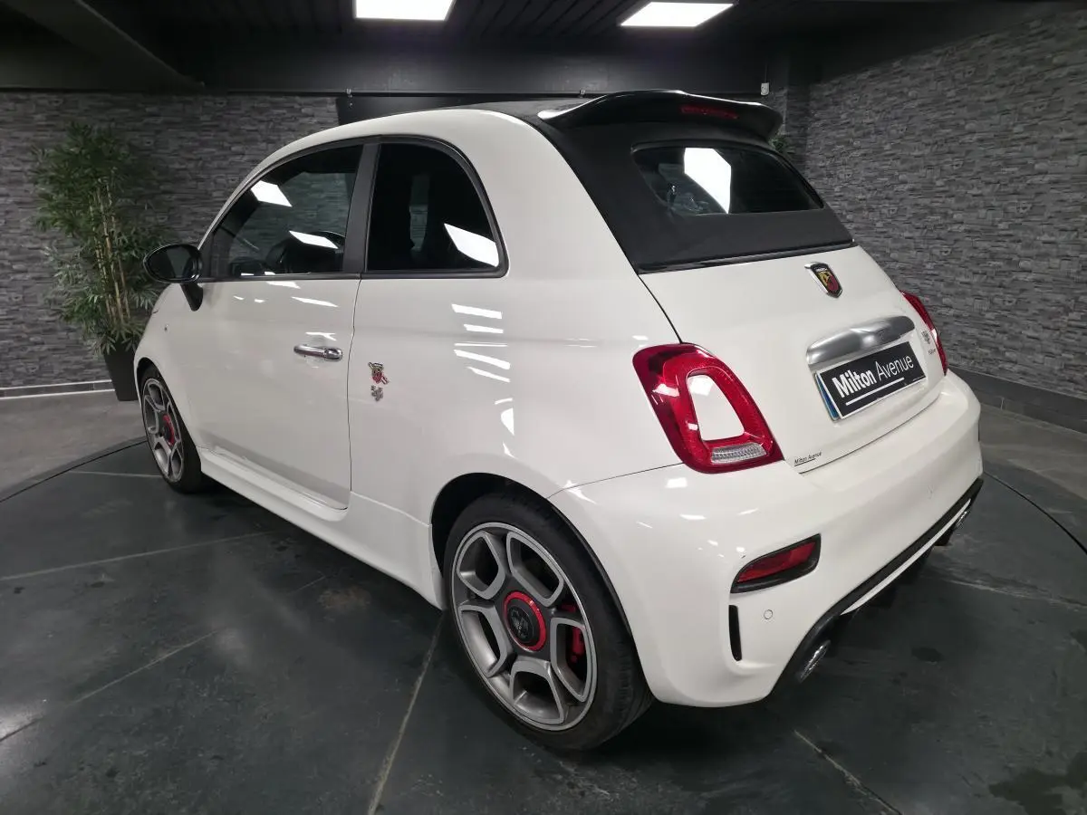 Vue 3/4 arrière droite de l'Abarth 595C Turismo blanc avec étriers de frein rouges et toit noir ouvrant.
