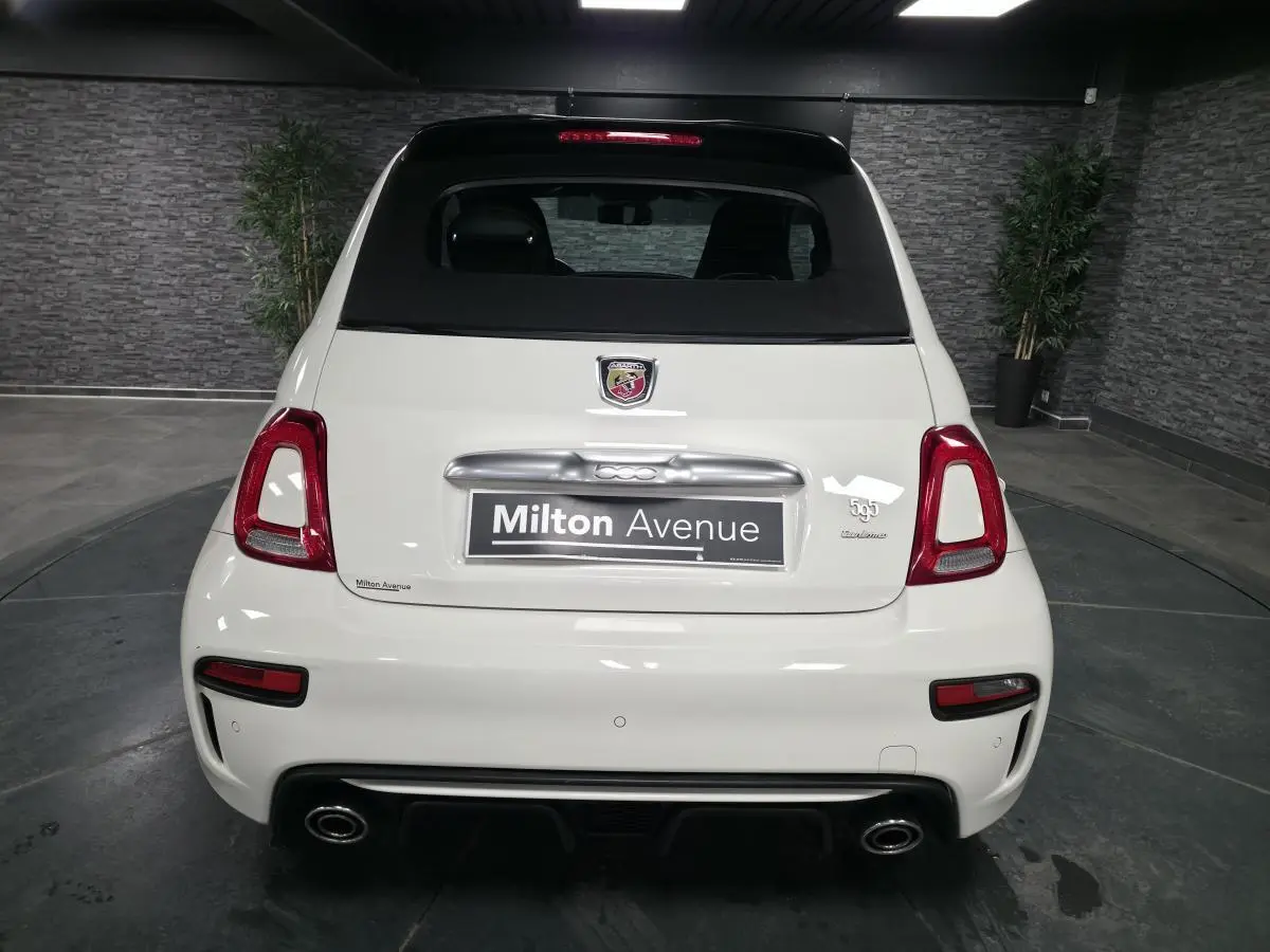 Vue arrière d'une ABARTH 500 blanche avec double sortie d'échappement chromée et toit noir en toile.