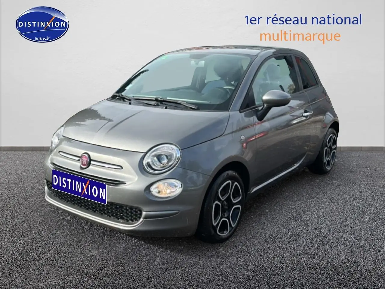 Fiat 500 gris vue 3/4 avant droit, avec phares ronds et jantes au design distinctif noir et argent.