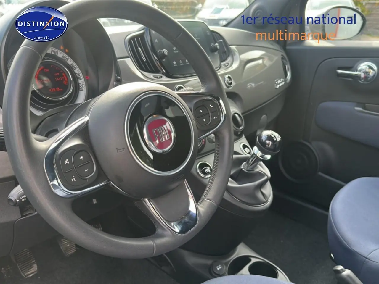 Vue intérieure côté conducteur du tableau de bord gris et volant cuir noir d'une Fiat 500 1.0 70 bsg cult avec boîte manuelle.