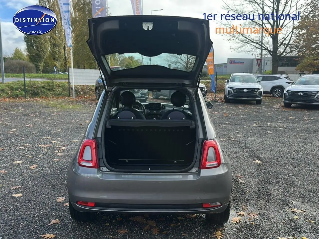 Vue arrière d'une Fiat 500 gris avec hayon ouvert, montrant l'intérieur et la banquette rabattable.