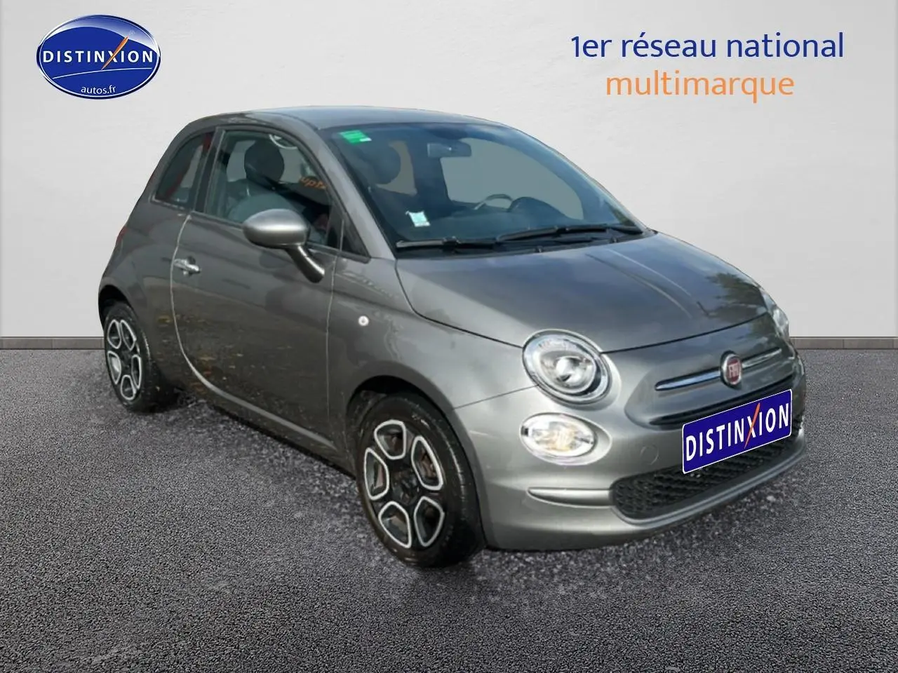 Fiat 500 gris vue 3/4 avant droit, avec jantes originales et phares ronds caractéristiques.