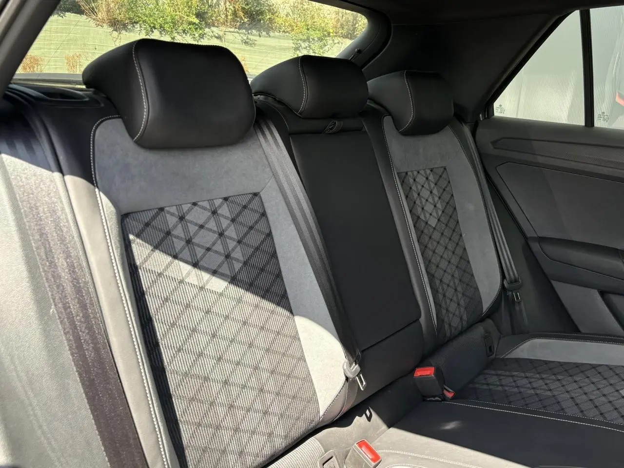 Vue intérieure arrière du Volkswagen T-Roc 1.5 TSI R-Line 2025, sièges cuir et alcantara gris avec surpiqûres blanches.