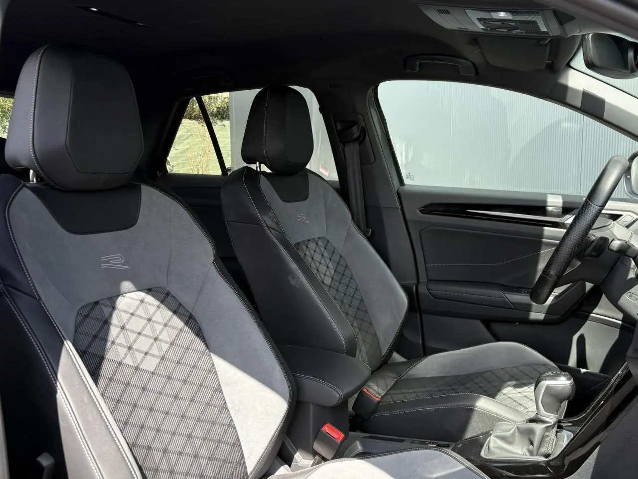 Vue intérieure côté droit montrant les sièges avant cuir et alcantara gris avec logo R-Line brodé sur un Volkswagen T-Roc 2025.