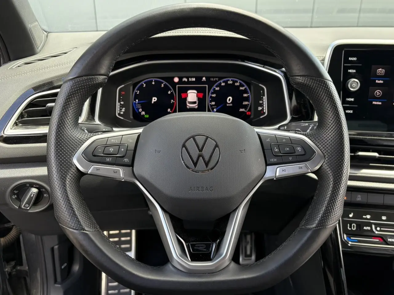 Vue frontale du volant cuir perforé noir avec logo R-Line et tableau de bord digital du Volkswagen T-Roc 2025.