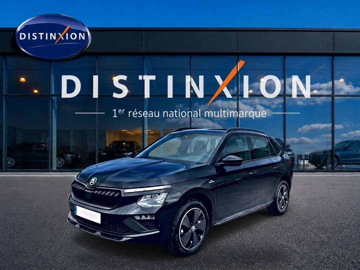 Vue 3/4 avant gauche d’un Skoda Kamiq noir Monte Carlo avec jantes alu distinctives, devant une vitrine Distinxion.