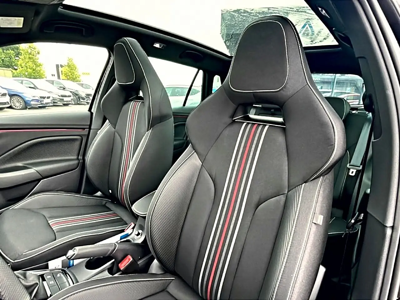 Vue intérieure des sièges avant sport noirs avec surpiqûres blanches et bandes rouges du Skoda Kamiq Monte Carlo 2026.