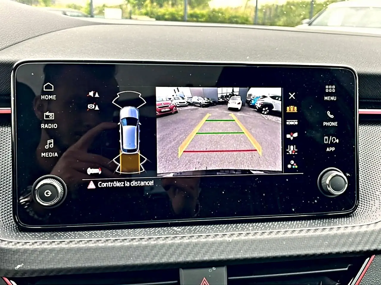 Écran tactile intérieur montrant la caméra de recul et l’aide au stationnement du Skoda Kamiq noir, vue de face.
