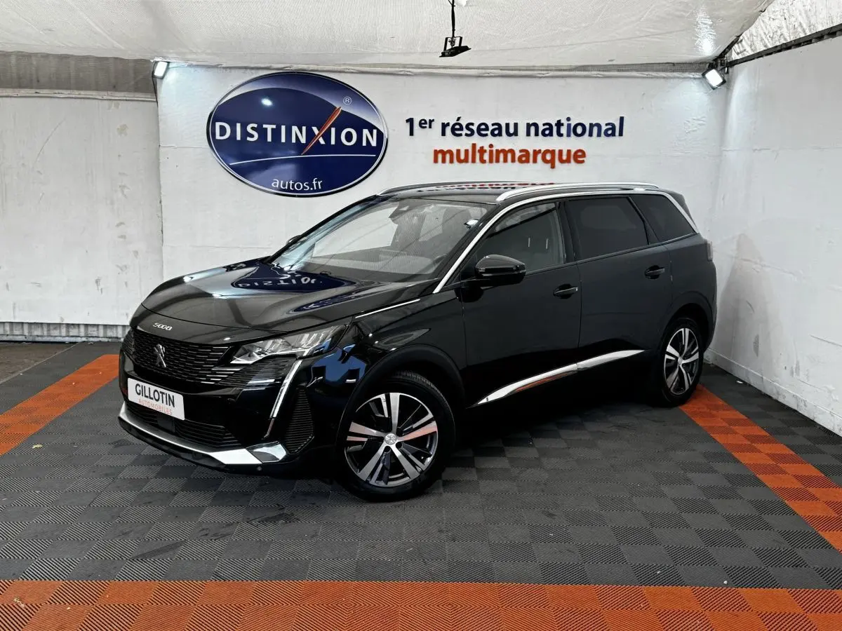 Peugeot 5008 noir vue 3/4 avant droit dans un showroom avec jantes alliage et vitres teintées.