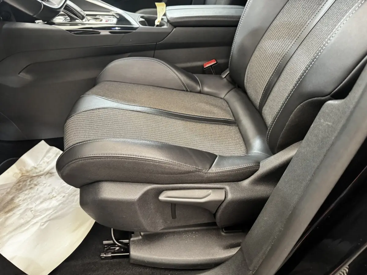 Gros plan sur le siège avant droit en cuir et tissu gris du Peugeot 5008 noir, avec levier de réglage manuel visible.