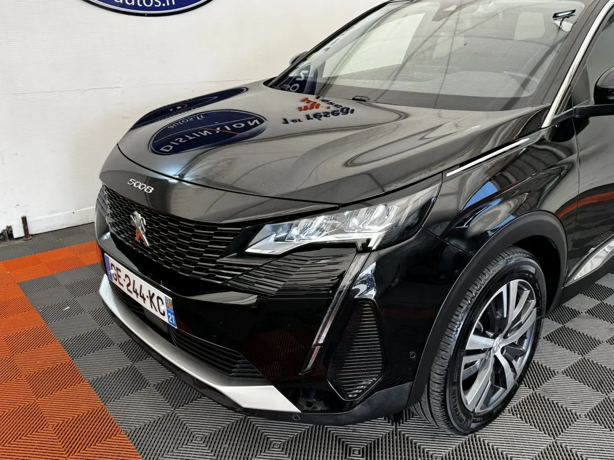 Vue 3/4 avant droit d’un Peugeot 5008 noir 2022 avec calandre noire et phares LED distinctifs.